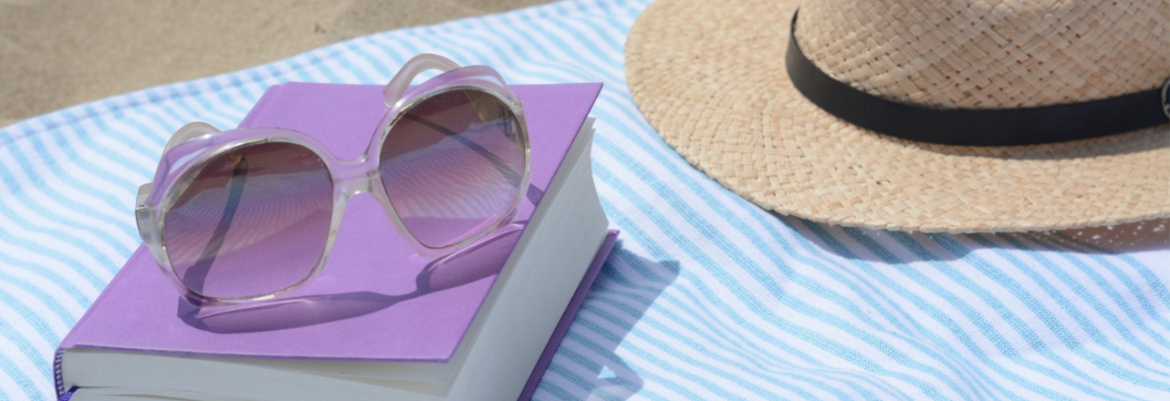 photo of a book, sunglasses and a beach hat