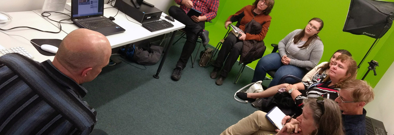 group sitting in digital media lab with green screen