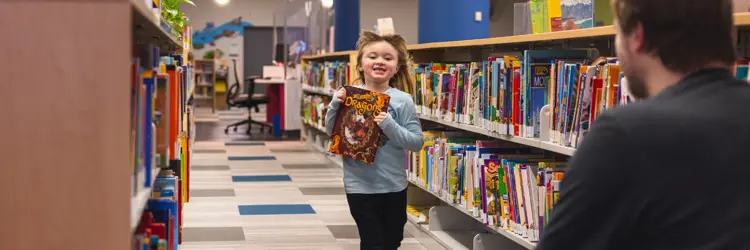 happy child holding a book running toward a parent